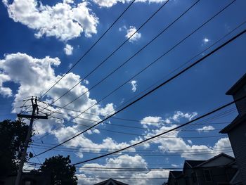 Low angle view of electricity pylon against cloudy sky