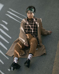 Portrait of a young man sitting on road