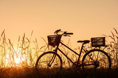 Silhouette bicycle on field against sky during sunset