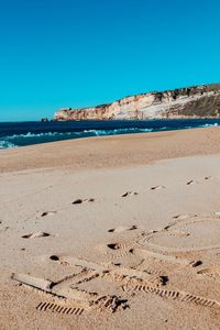 Scenic view of beach against clear blue sky
