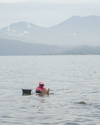 Man in boat on sea against mountains