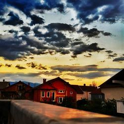 Houses against cloudy sky at sunset