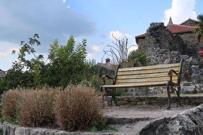 Empty bench in park against sky