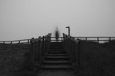 Steps leading towards sea against clear sky