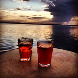 Close-up of beer on beach against sky during sunset