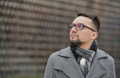 Young man wearing sunglasses standing against wall