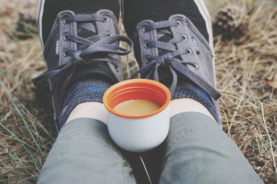 Low section of person wearing shoes sitting on field