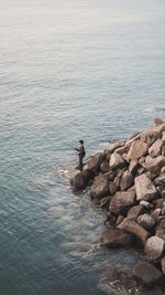 Side view of man on rocks by sea