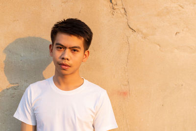 Portrait of young man standing against wall