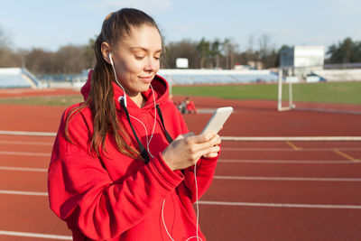 Woman using mobile phone while standing on running track