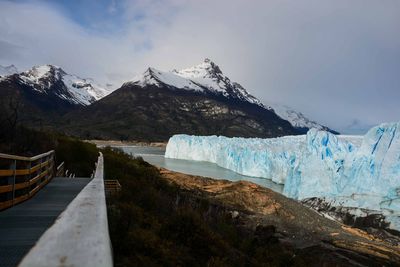 Pathway leading towards snowcapped mountains against sky