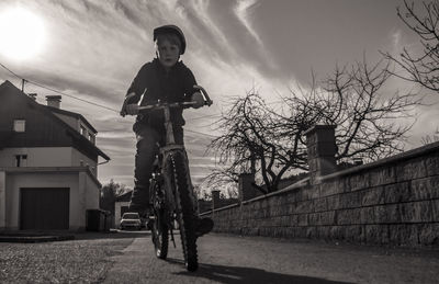 Low angle view of boy standing on house against sky