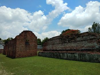 Old building on field against cloudy sky