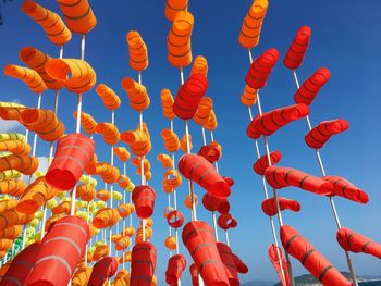 Low angle view of orange flags hanging against sky