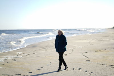 Full length of woman walking on beach against sky
