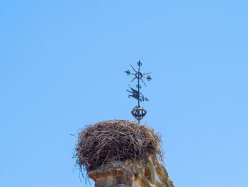 Low angle view of weather vane against clear blue sky