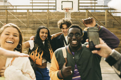 Cheerful male and female friends enjoying while dancing in basketball court