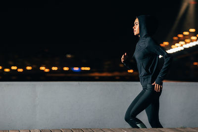Side view of man looking at illuminated city at night
