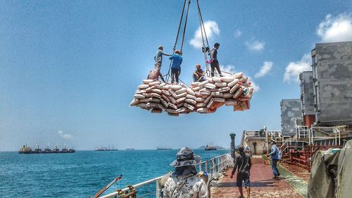 People at harbor by sea against sky