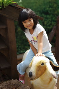 Portrait of cute smiling girl sitting on artificial sheep