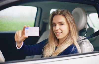 Portrait of smiling young woman holding credit card in car