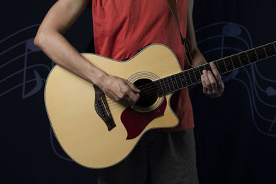 Midsection of man playing guitar