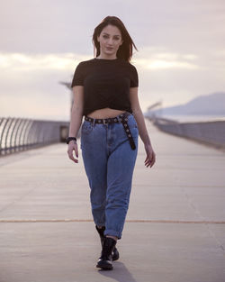 Portrait of young woman standing against sky