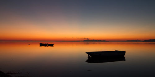 Silhouette of three boats at sunset, floating in a standing water