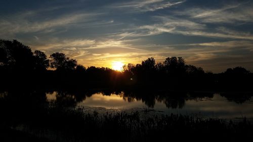 Reflection of trees in lake during sunset