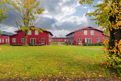 Several identical red wooden houses stand on a field with green grass. copenhagen, denmark