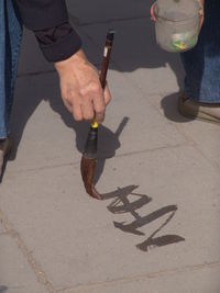 Low section of man with umbrella on street