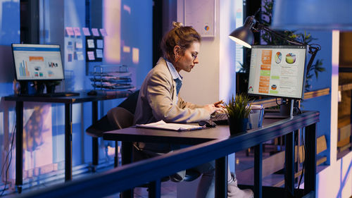 Young woman using mobile phone while sitting on table