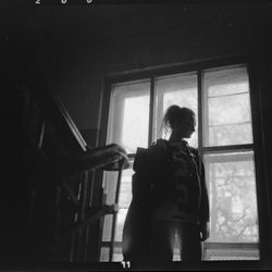 Rear view of woman looking through window at home