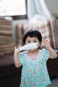 Portrait of cute girl holing mask sitting at home