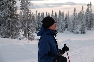 Side view of man holding ski pole on field during winter