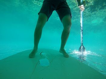 Low section of man swimming in pool