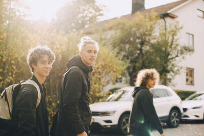 Friends standing on car against trees