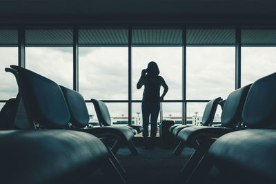 Rear view of woman standing at airport departure area