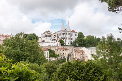 Low angle view of trees and buildings against sky