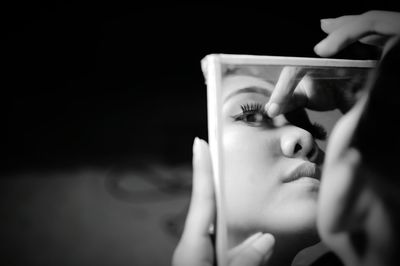 Close-up of woman applying make-up reflecting on mirror