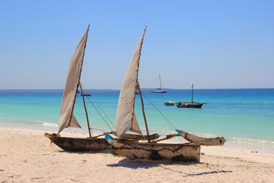 Nautical vessel on beach against clear blue sky