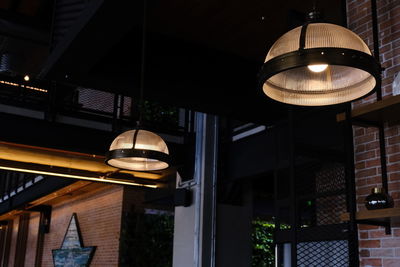 Low angle view of illuminated pendant light hanging in building at night
