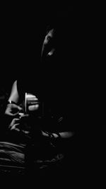Midsection of woman sitting in darkroom