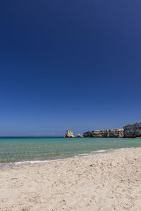 Scenic view of beach against clear blue sky