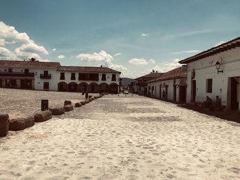 Empty alley amidst buildings in city against sky