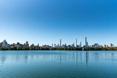 Panoramic view of river and buildings against clear blue sky