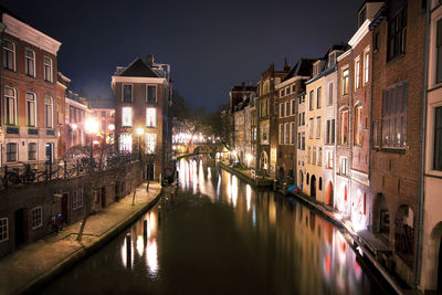 Canal amidst buildings in city at night