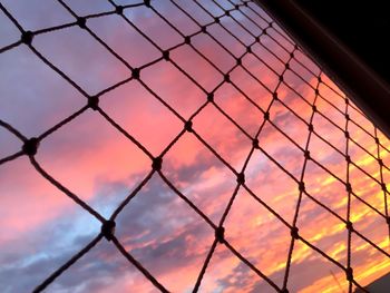 Low angle view of chainlink fence against sunset sky