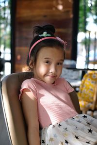 Portrait of cute girl sitting on chair at home