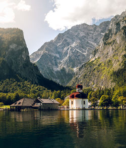 Houses by lake and mountains against sky